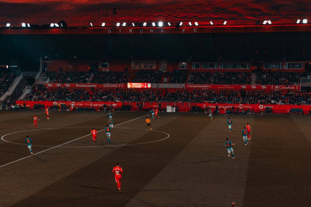 Stadion sepak bola dengan lampu sorot menyala pada malam pertandingan
